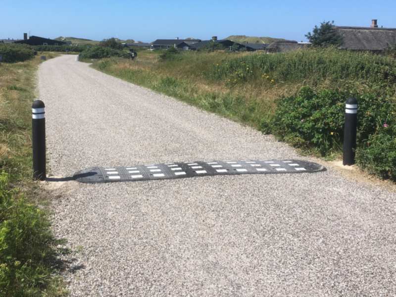 TDJ Vejbump 30 km/t med pullert. Bump på grusvej ved sommerhusområde. Typegodkendt af vejdirektoratet. Trafikgummi.dk